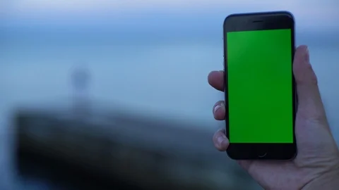 Concept view of smartphone with greenscreen chromakey tracking matte on seafront Stock Footage 118208154