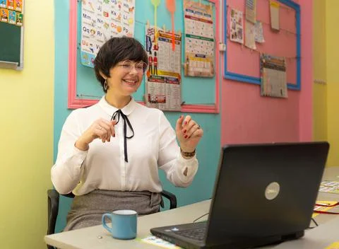 The concept of virtual learning. A young school teacher of English studies Stock Photos