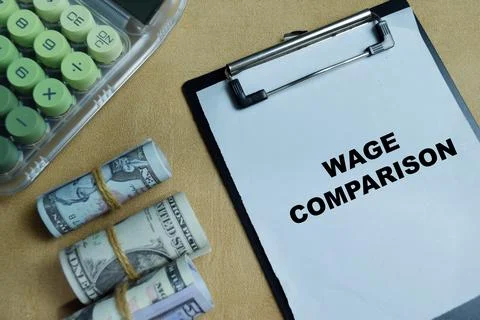 Concept of wage comparison write on clipboard isolated on Wooden Table. Stock Photos