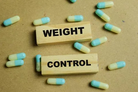Concept of weight control with pills text on wooden blocks. Stock Photos