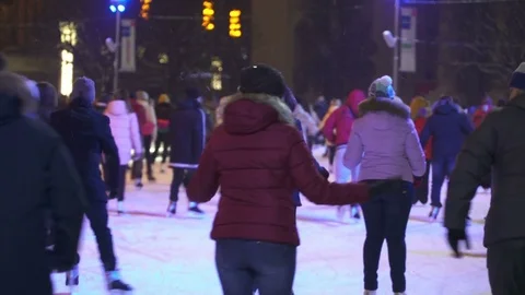 Concept Winter and Snow. Crowd at Night City Skating Rink. Falling Snow. Stock Footage 70408304