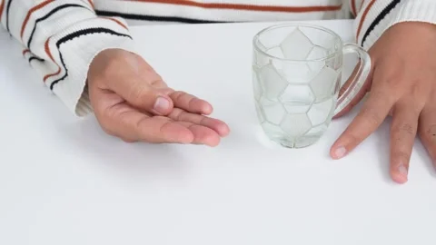 Concept of a woman taking medicine while holding water in a glass Stock Footage 339268161