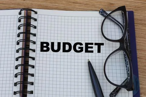 Concept word budget on a sheet of notepad with a pen and glasses Stock Photos