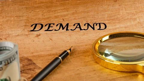 Concept word DEMAND on papyrus in a composition with a magnifying glass, foun Stock Photos