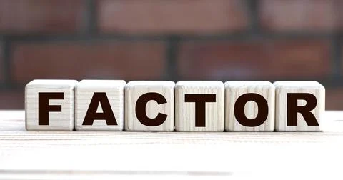 Concept word FACTOR on cubes against the background of a brick wall Stock Photos