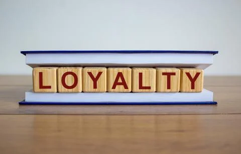 Concept word 'loyalty' on wooden cubes between pages of a book on a beautiful Stock Photos