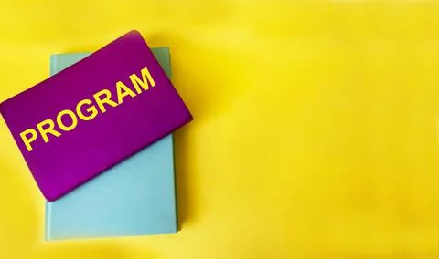 Concept of the word PROGRAM on a crimson notebook and on a yellow background. Stock Photos