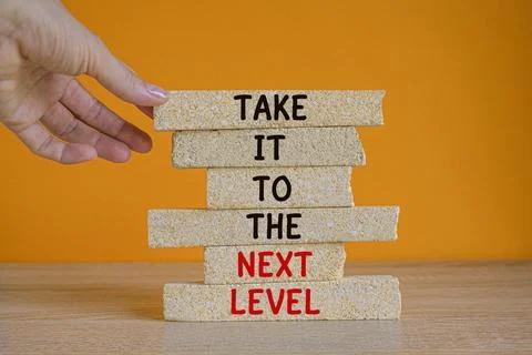 Concept words Take it to the next level on brick blocks. Businessman hand. Stock Photos