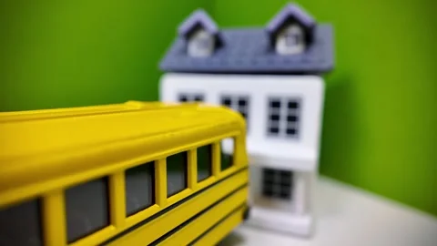 Concept of Yellow toy school bus driving away from home Stock Footage 339263467
