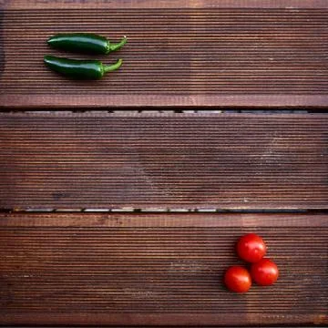 A conceptual composition of red cherry tomatoes and hot green chili peppers o 스톡 사진