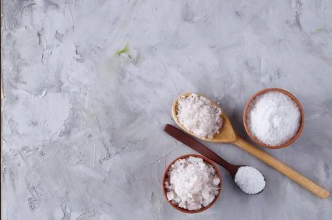 Conceptual composition of salt and pepper on spoons and bowls over light Stock Photos