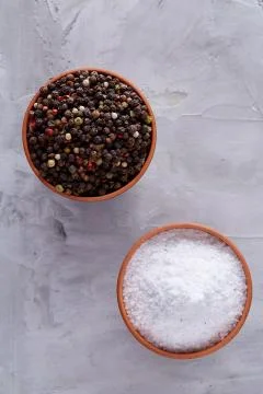 Conceptual composition of salt and pepper on spoons and bowls over light Stock Photos
