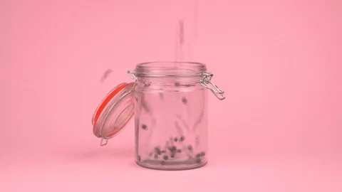 Conceptual image of black beans falling on jar glass over pastel background. Stock Footage 106805874