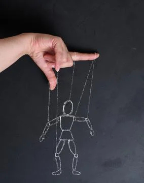 Conceptual image of manipulation, a human hand holding strings leading to a.. Foto stock
