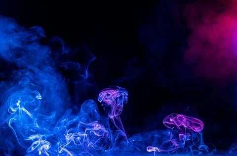 Conceptual image of multi-colored smoke isolated on dark black background, Ha Stock Photos