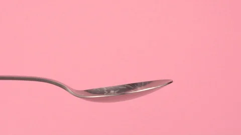 Conceptual image of white sugar falling on spoon with pastel background. Video stock 106807381