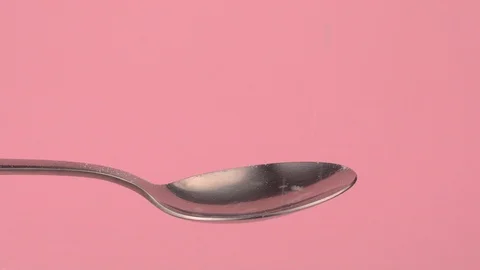 Conceptual image of white sugar falling on spoon with pastel background. Stock Footage 106807411