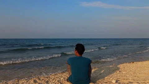 Conceptual man sitting alone in the beach Stock Footage 235794764