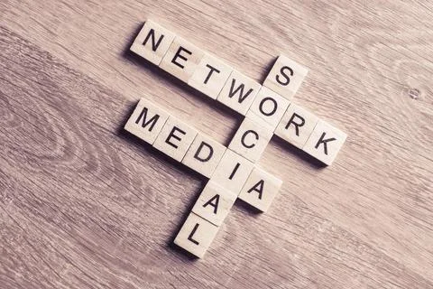 Conceptual media keywords on table with elements of game making crossword Foto stock