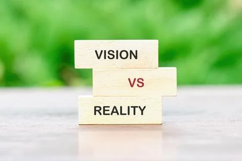 A conceptual representation displaying VISION versus REALITY on light wooden  Foto stock