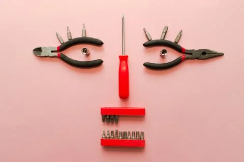 Conceptual set of tools on pink background. It looks like a woman face. Worki Stock Photos