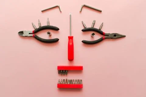 Conceptual set of tools on pink background. It looks like a woman face. Worki Stock Photos