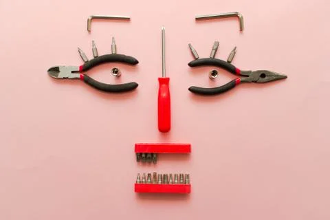 Conceptual set of tools on pink background. It looks like a woman face. Worki Stock Photos