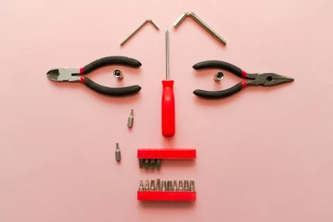 Conceptual set of tools on pink background. It looks like a woman face. Worki Stock Photos