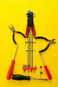 Conceptual set of tools on yellow background. It looks like guitar. Working h Stock Photos