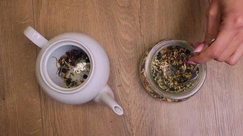 Conceptual shot from above of how hands add tea leaves to a teapot, a spoon Видео 263183976