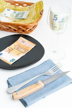 Conceptual studio shot of dinner table with euro bank notes on the plate instead Stock Photos