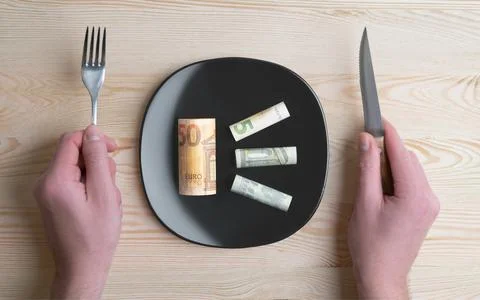 Conceptual studio shot of dinner table with euro bank notes on the plate instead Stock Photos