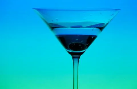 Conceptually illuminated martini glass on gradient background Stock Photos
