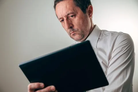 Concerned businessman analyzing financial data on a digital tablet, showing.. Stock Photos