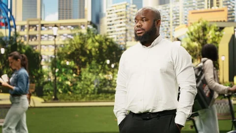 Concerned businessman checking time on smartwatch while standing in city park Stock Footage 343499767