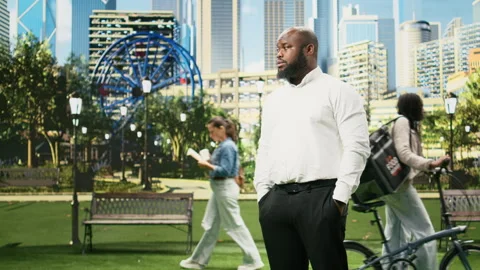 Concerned businessman checking time on smartwatch while standing in city park Stock Footage 343506617