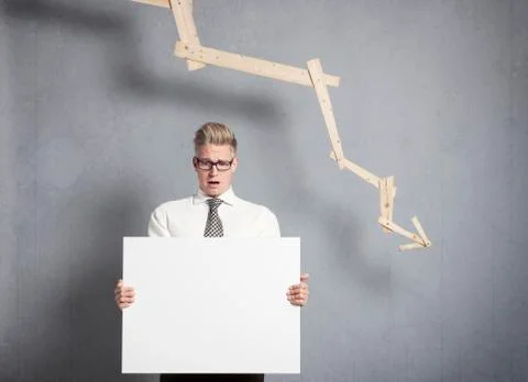 Concerned businessman presenting panel in front of descending graph. Stock Photos