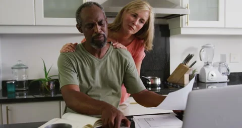 Concerned diverse senior couple using laptop computer paying bills in kitchen Stockbeeldmateriaal 148890085