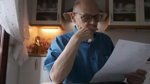 Concerned Elderly Man Reading Document in Kitchen Stock Footage 309098901