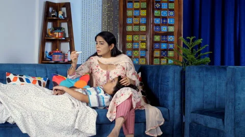 A concerned Indian mother checking the body temperature of her sick son - par... Stock Footage 169856176