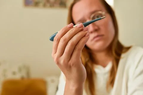 A Concerned Look While Checking Her Temperature at Home Stock Photos