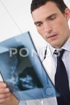 Concerned male doctor looking at x-ray Stock Photos