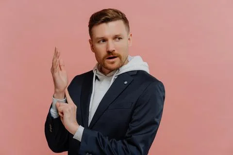 Concerned man checking his pulse rate while standing against pink wall in studio Stock Photos