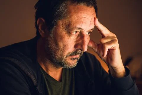 Concerned man looking at computer screen and thinking in dark room illumina.. Stockfoto's