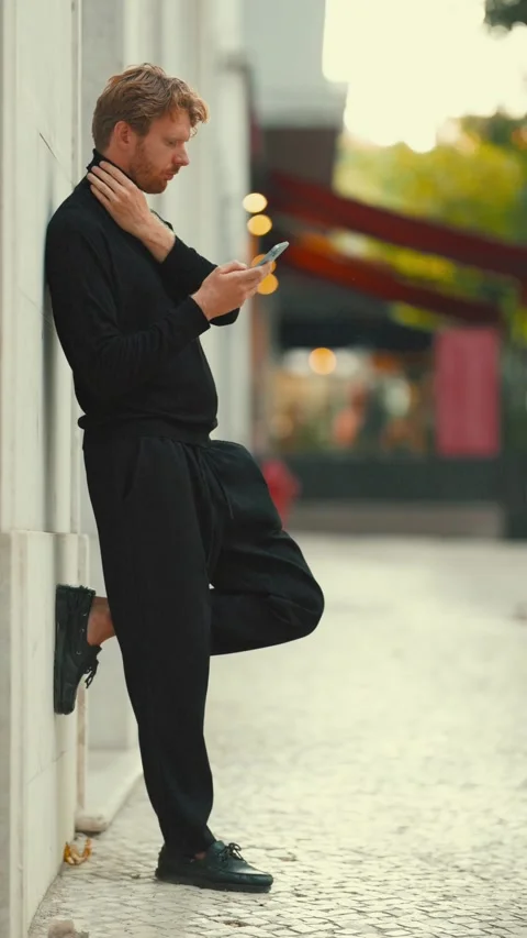 Concerned man using smartphone leaning against a wall Stock Footage 346400213