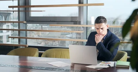 Concerned man working on laptop computer and looking away thinking solving 库存影片 122165723