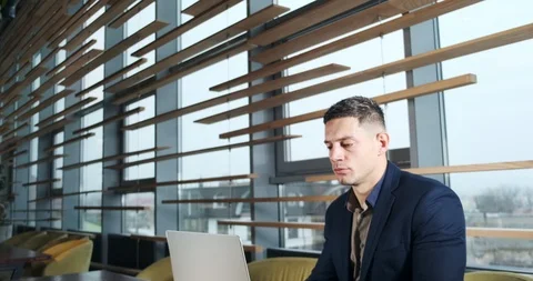 Concerned man working on laptop computer and looking away thinking solving 库存影片 122536394