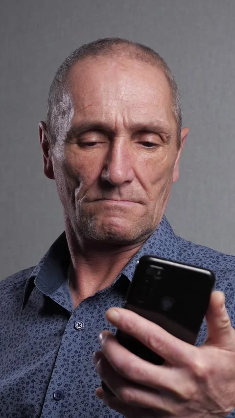 Concerned mature man using a smartphone and looking at the screen with a serious Stock-Footage 340846572