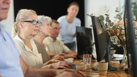 Concerned old woman sitting at computer while trainer speaking on the background Stock Footage 306448503