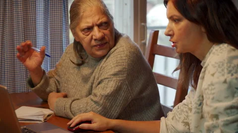 Concerned Older Woman Learns, Taking Notes While Daughter Uses Laptop. Vídeos de archivo 321155407